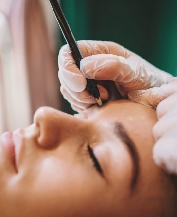Brows - Women getting some of her right eyebrow hairs removed with tweezers